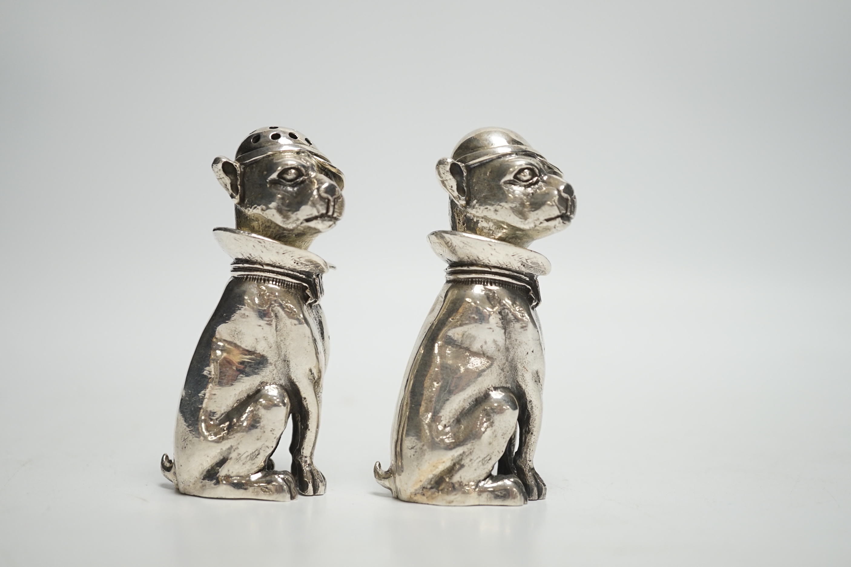 A novelty pair of 925 pepperettes, modelled as seated dogs, wearing caps, 76mm, 6.3oz.